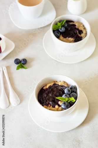 Porridge with blueberry sauce decorated fresh blueberries and mint. 