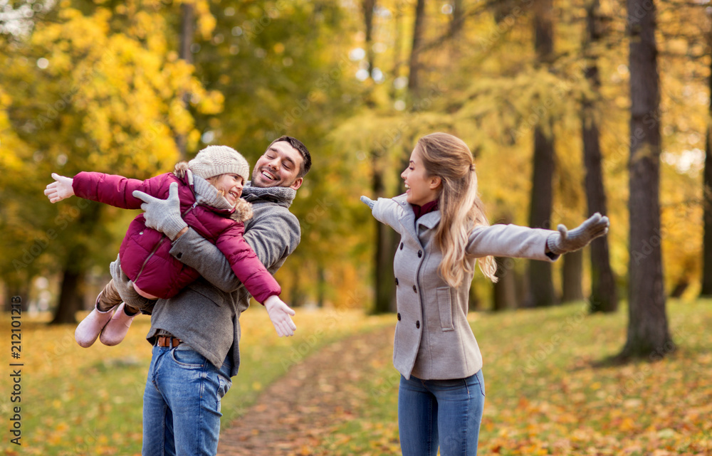 Fototapeta premium family, season and people concept - happy mother, father and little daughter playing at autumn park