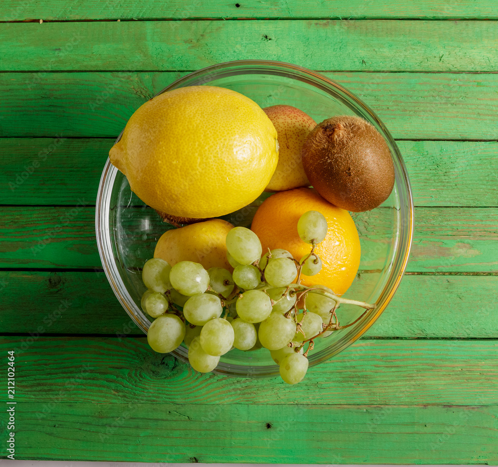 Fruit in a glass dish on a green wooden background. Fruit in a glass dish on a green wooden background.
