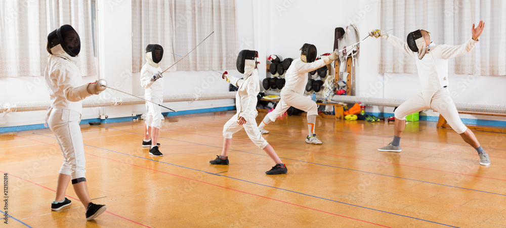 Kids with adults practicing fencing techniques