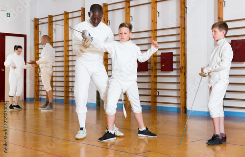 Fencing instructor with young fencers in training room