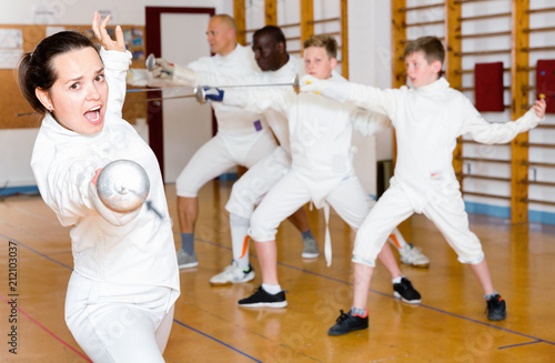 Young woman fencer practicing effective fencing techniques in training room