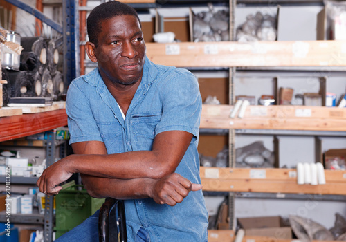 Portrait of confident African American man standing among shelves with materials for renovation works