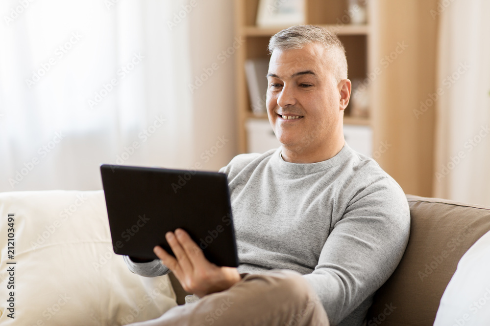 technology, people and lifestyle concept - man with tablet pc computer sitting on sofa at home technology, people and lifestyle concept - man with tablet pc computer sitting on sofa at home