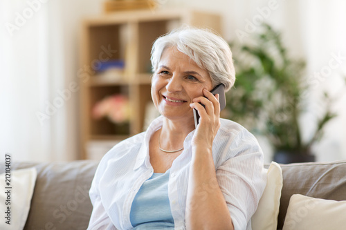 technology, communication and people concept - happy senior woman calling on smartphone at home photo