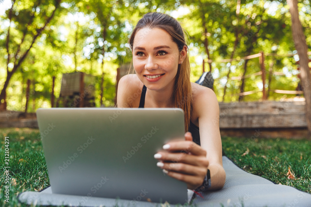 Portrait of a smiling young fitness girl using laptop Portrait of a smiling young fitness girl using laptop