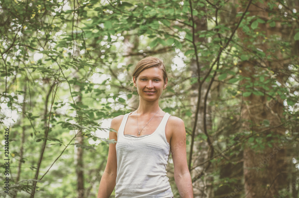 Smiling young woman in a white tank top in the forest Smiling young woman in a white tank top in the forest
