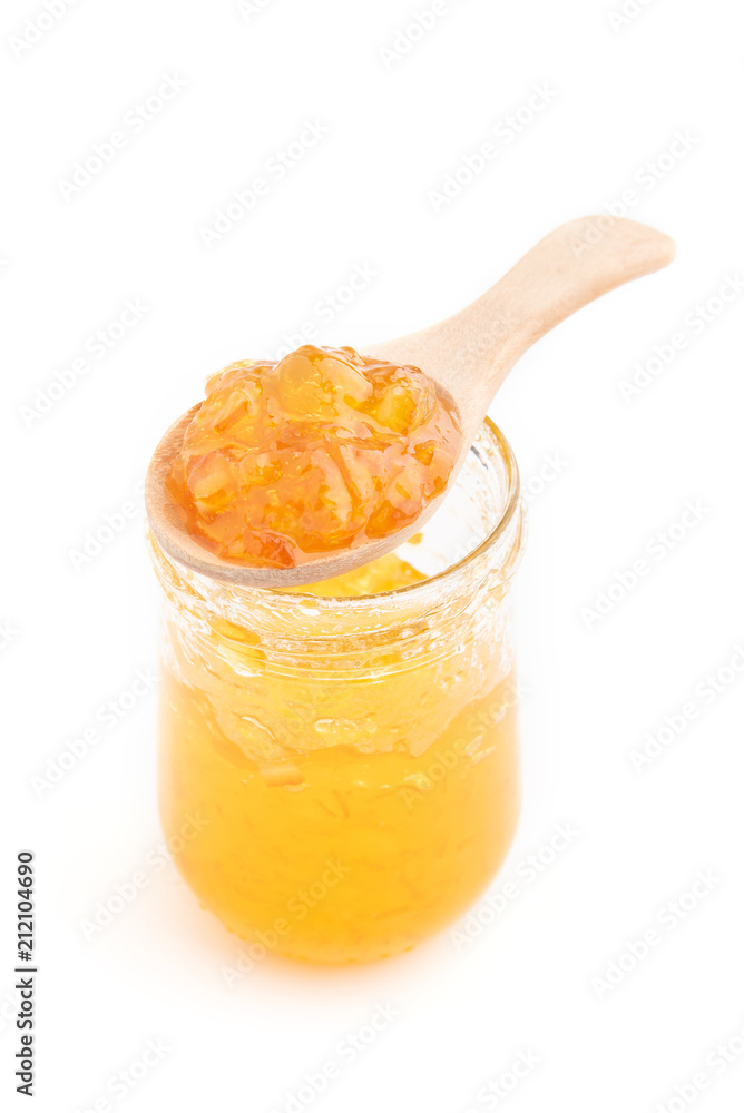 Open jar of orange jam and a spoon, isolated on white. Open jar of orange jam and a spoon, isolated on white.
