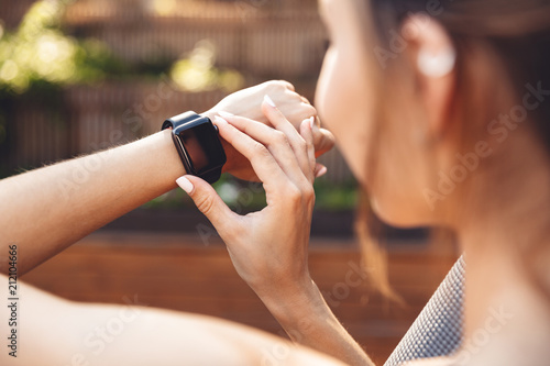 Close up of a young fitness girl checking her smart watch