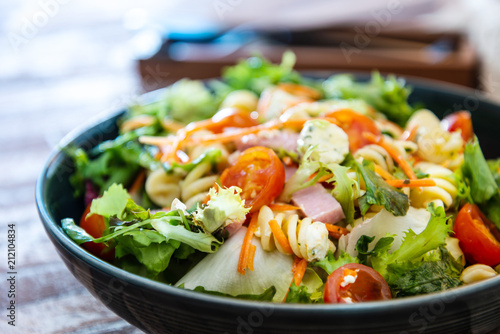 Salad with fusilli pasta accompanied tomatoes, mozzarella, smoked ham and italian cheese