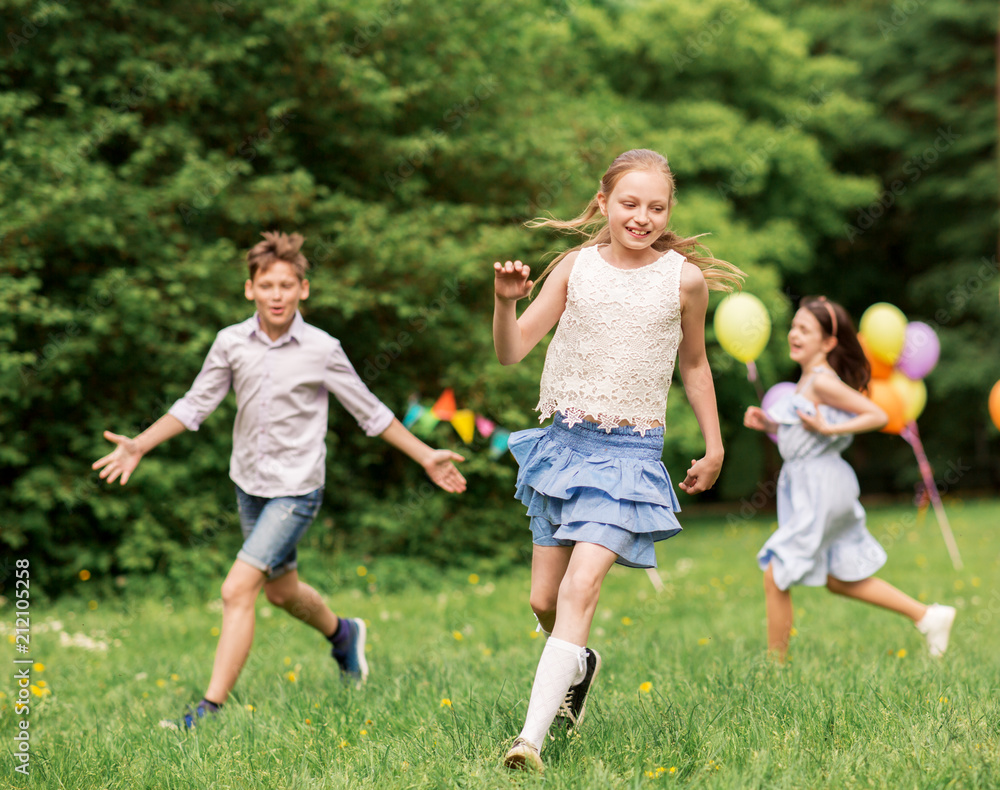 Fototapeta premium friendship, childhood, leisure and people concept - group of happy kids or friends playing tag game at birthday party in summer park