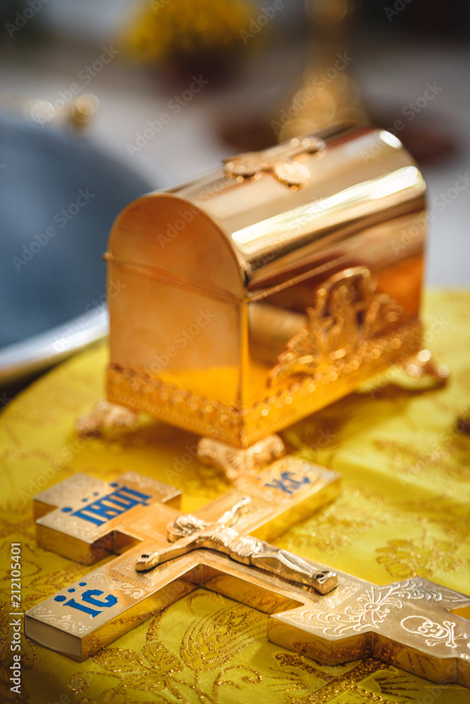 Christening in the church, golden religious utensils: bible, cross, prayer book, missal. Details in the orthodox christian church Christening in the church, golden religious utensils: bible, cross, prayer book, missal. Details in the orthodox christian church