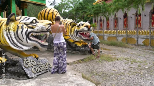 A woman is taking pictures of a man with a tiger statue. photo