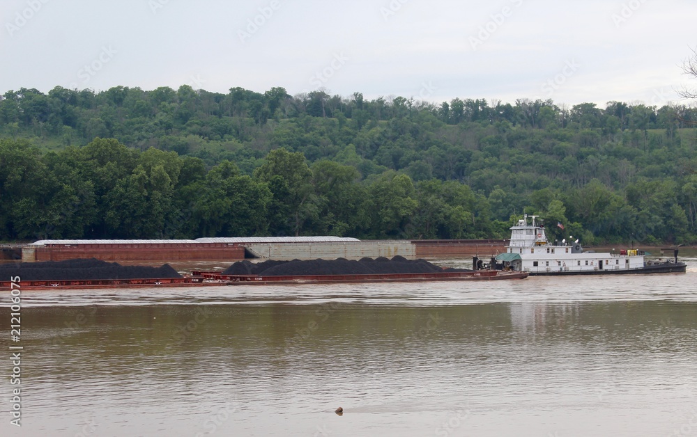 The barge pushing coal up the flowing river.