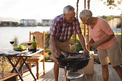 Senior couple cooking fish on barbeque photo