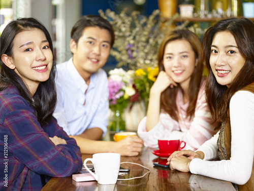 happy young asian adults looking at camera smiling in coffee shop