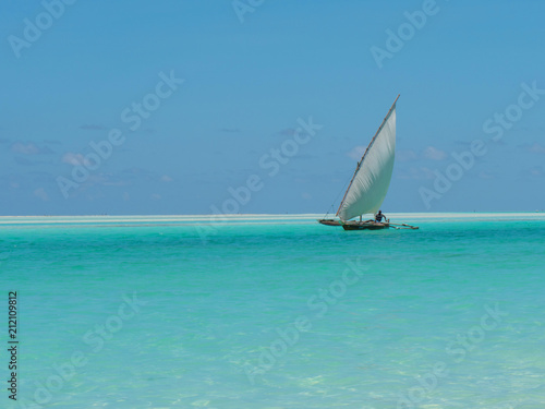 Fisherman fishing and sails on a wooden boat on clear blue water along a tropical exotic beach in Africa. Indian Ocean, Zanzibar
