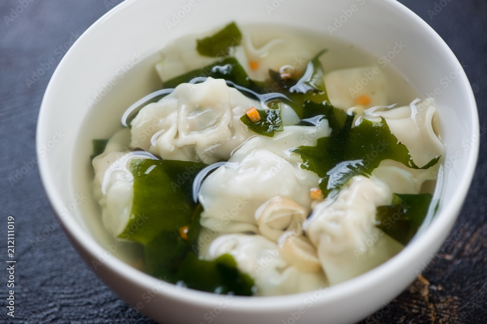 White bowl of chinese soup with wonton dumplings, close-up, horizontal shot White bowl of chinese soup with wonton dumplings, close-up, horizontal shot