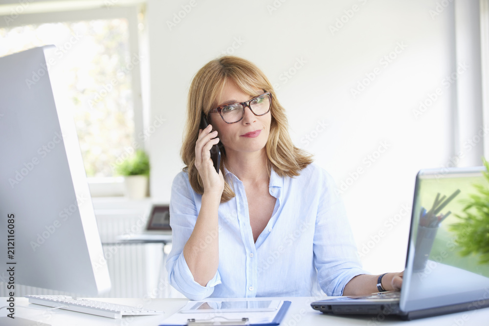 Successful businesswoman using her mobile phone at the office Successful businesswoman using her mobile phone at the office