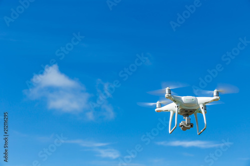 Flying drone quadcopter with digital camera on blue sky