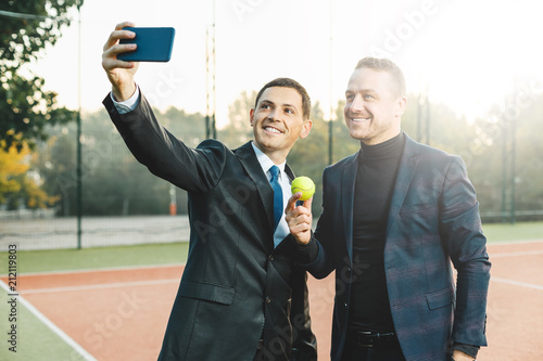 Business men taking selfie on a tennis court photo