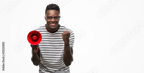 Young african american man holding megaphone screaming proud and celebrating victory and success very excited, cheering emotion