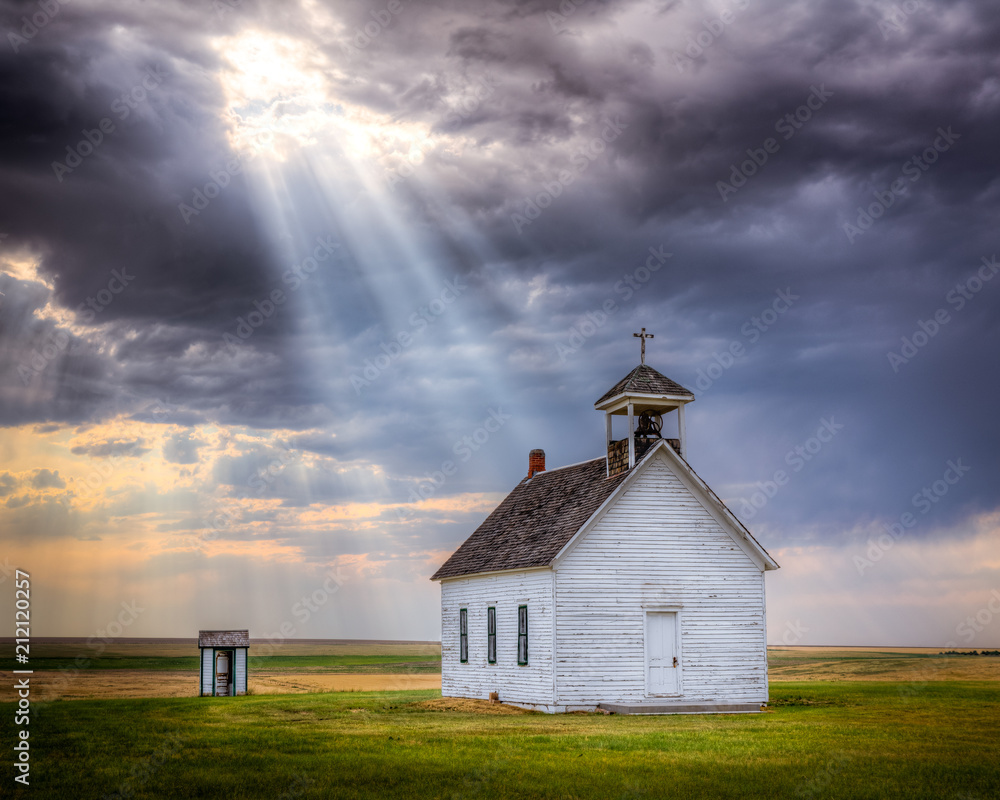 Old abandoned church at sunset with a beam of light shining down upon it.