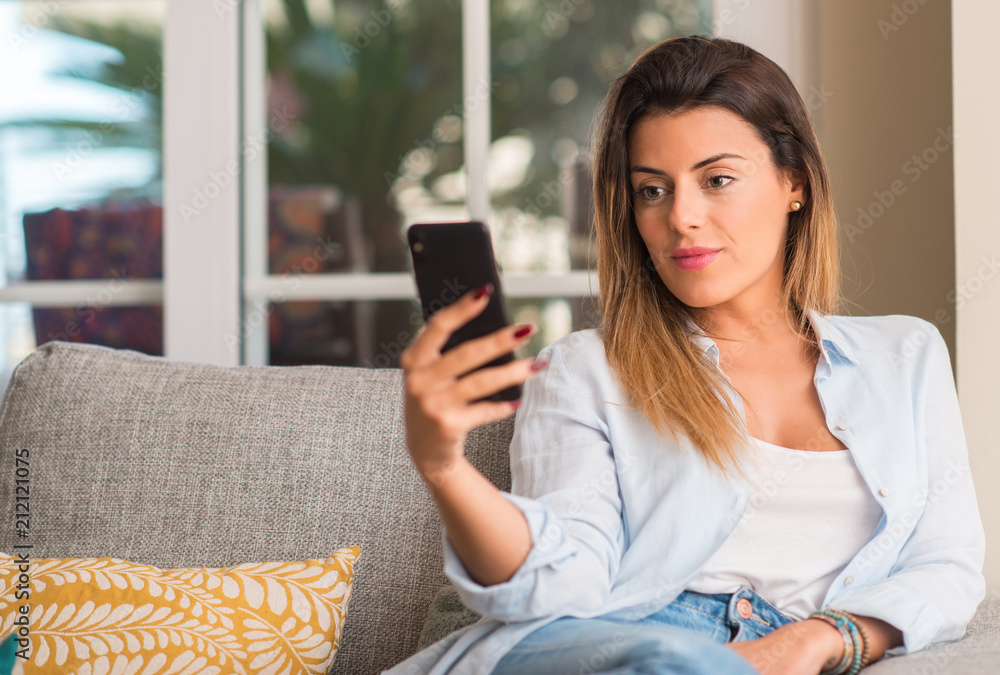 Young beautiful woman talking on the phone on the sofa looking confident. Young beautiful woman talking on the phone on the sofa looking confident.