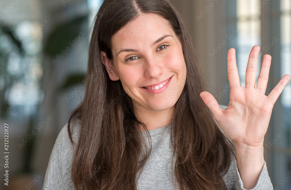 Young beautiful woman at home showing and pointing up with fingers number five while smiling confident and happy.