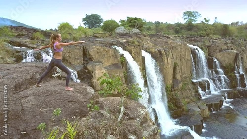 drone removes from girl changing yoga pose by waterfall photo