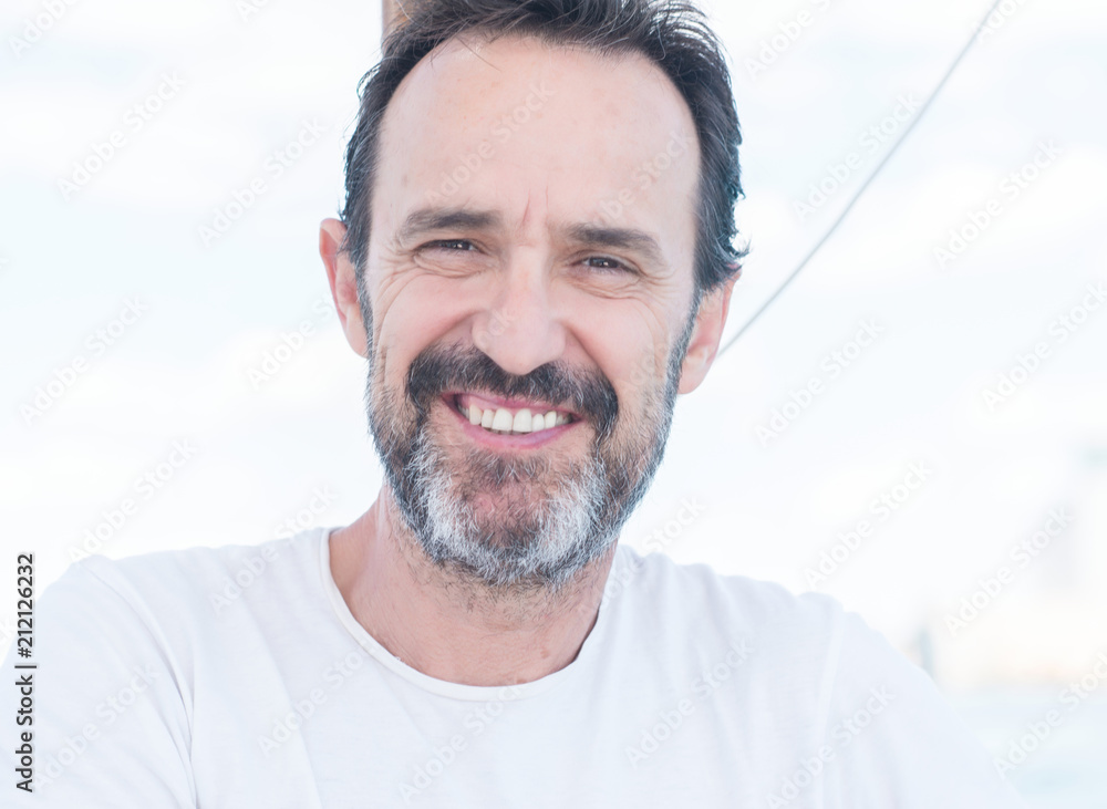 Fototapeta premium Handsome senior man traveling on sailboat and smiling happy and confident