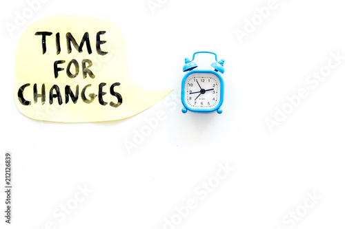 Time for changes hand lettering near alarm clock on white background top view copy space