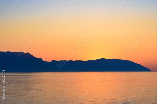Red sunset over Greek islands in calm sea 