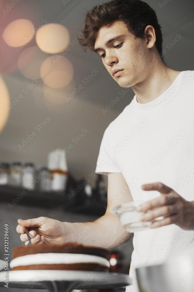 Young attractive man baking chocolate cake with butter cream. Young attractive man baking chocolate cake with butter cream.