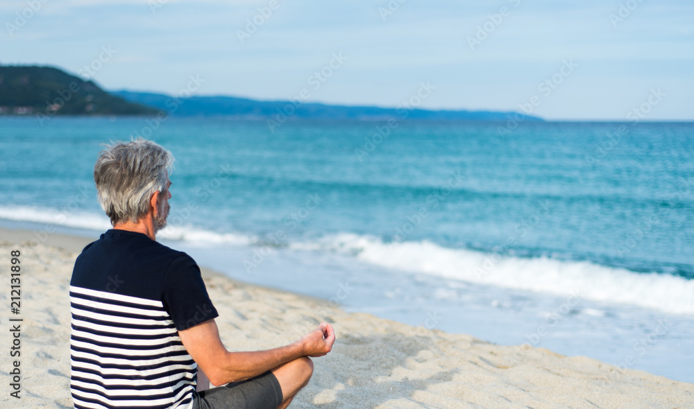 Senior man meditating on the beach