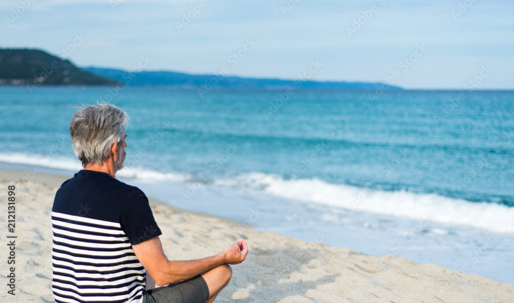 Fototapeta premium Senior man meditating on the beach