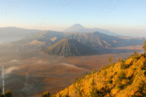 Splendid views of foggy sunrise of Bromo Tengger Semeru National Park with Mount Bromo in the center and low clouds by the open field in East Java, Indonesia. Volcanic landscape at dawn