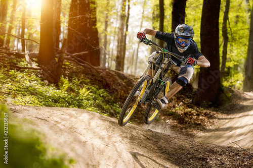 The cyclist on the downhill bike goes through the forest photo