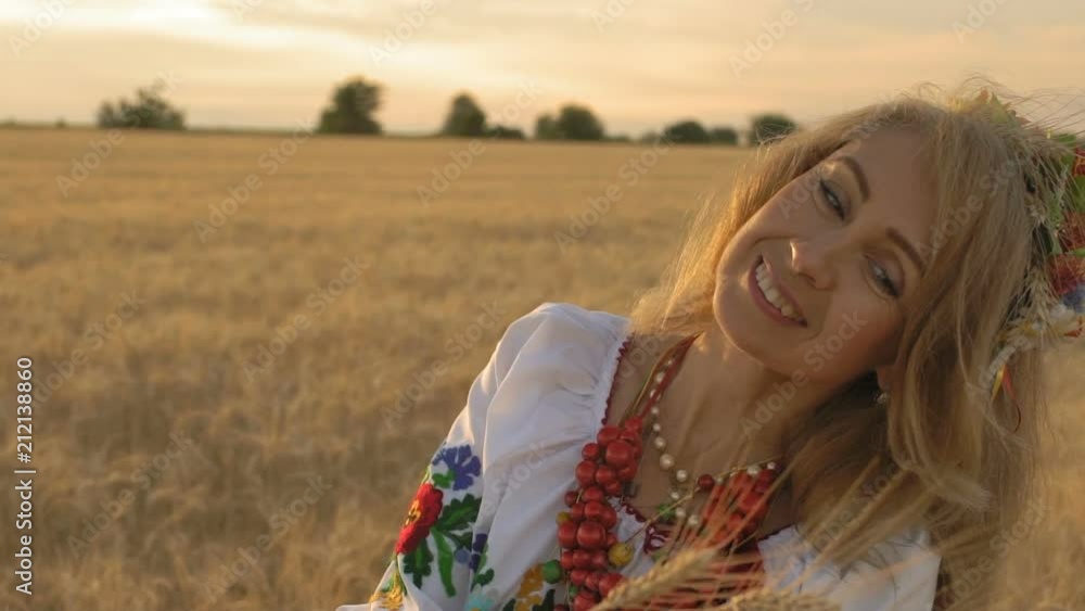 Slow Motion, Close-up, Beautiful Woman in National Costume on Wheat Field Looks Wheat Spikes in Hands and Smiles Slow Motion, Close-up, Beautiful Woman in National Costume on Wheat Field Looks Wheat Spikes in Hands and Smiles