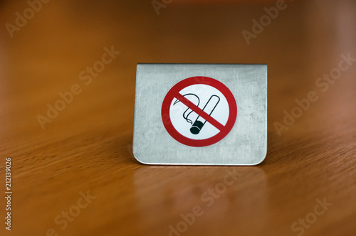 A metal sign no Smoking on the table in the hotel.
