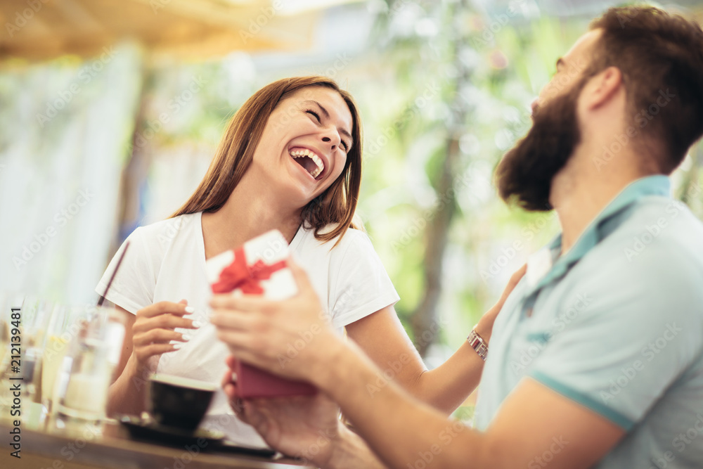 Man surprises woman with a gift in cafe Man surprises woman with a gift in cafe