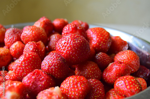 large red berries of juicy strawberry are in a bowl. Close up, beige background