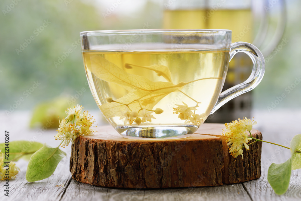 Φωτογραφία Cup of fresh tea from linden leaves in transparent dishes on a wooden stand, clo
