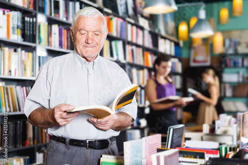 Mature smiling male customer is choosing book