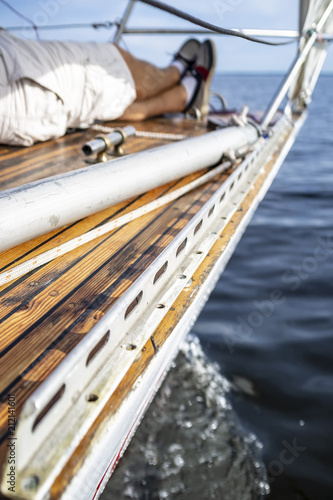 The man crossed his legs and lay relaxed on the deck of the yacht, on a blurred background of the sea and sky, a sunny day.