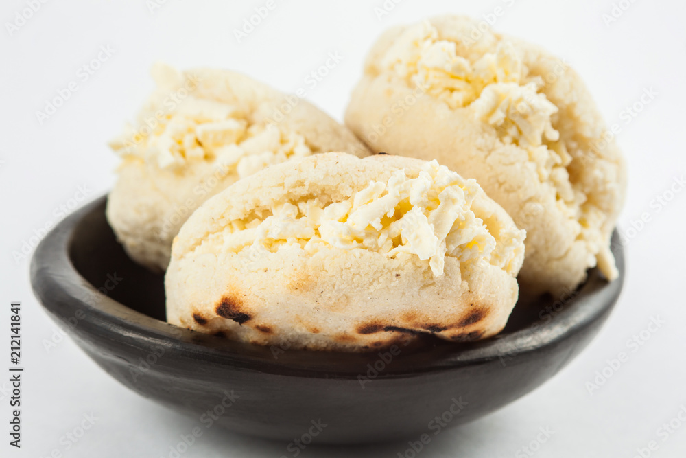 Colombian traditional white corn arepa stuffed with grated cheese in a black ceramic dish on black background Colombian traditional white corn arepa stuffed with grated cheese in a black ceramic dish on black background