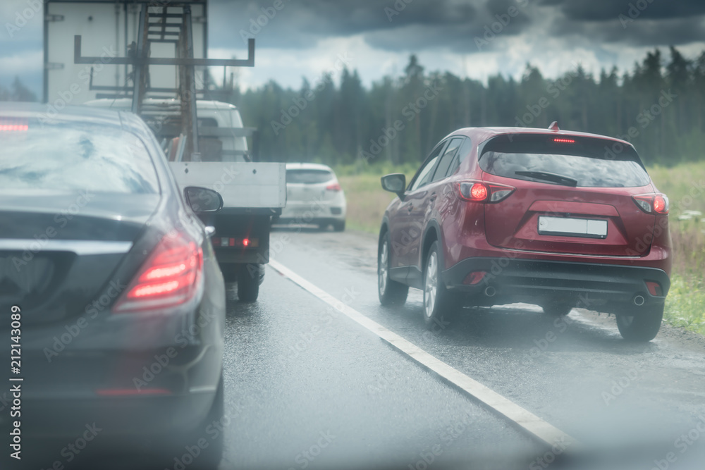 The car goes around the traffic jam on the side of the road. Violation of traffic rules. Lots of water drops. Dark stormy sky with clouds The car goes around the traffic jam on the side of the road. Violation of traffic rules. Lots of water drops. Dark stormy sky with clouds