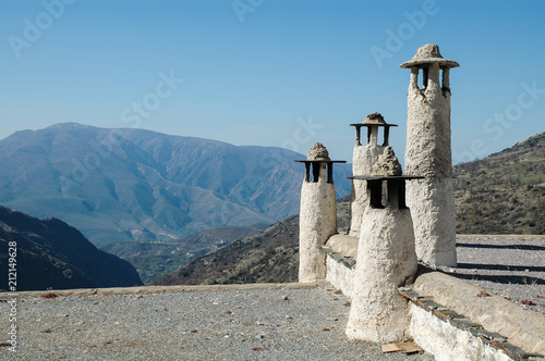 A group of four chimney pots on the roof of a house in the traditional design for the Alpujarra region of Spain. photo