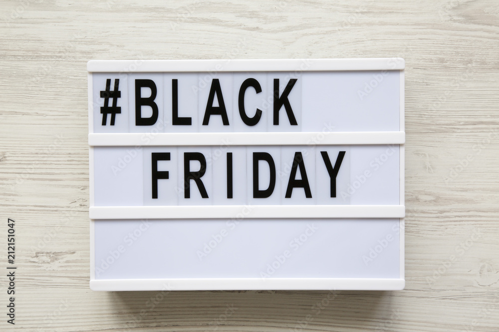 Black friday word on modern board over white wooden background, top view.