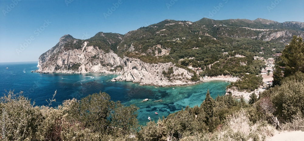 Beautiful summertime panoramic seascape. View of the cliff into the crystal clear azure sea bay and distant islands. Unique secluded beach. Agios Stefanos cape. Afionas. Corfu. Greece.